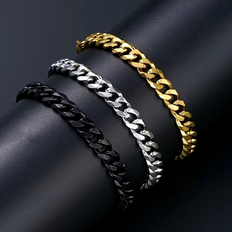Gold, steel and gunmetal Cuban link bracelets draped in low light